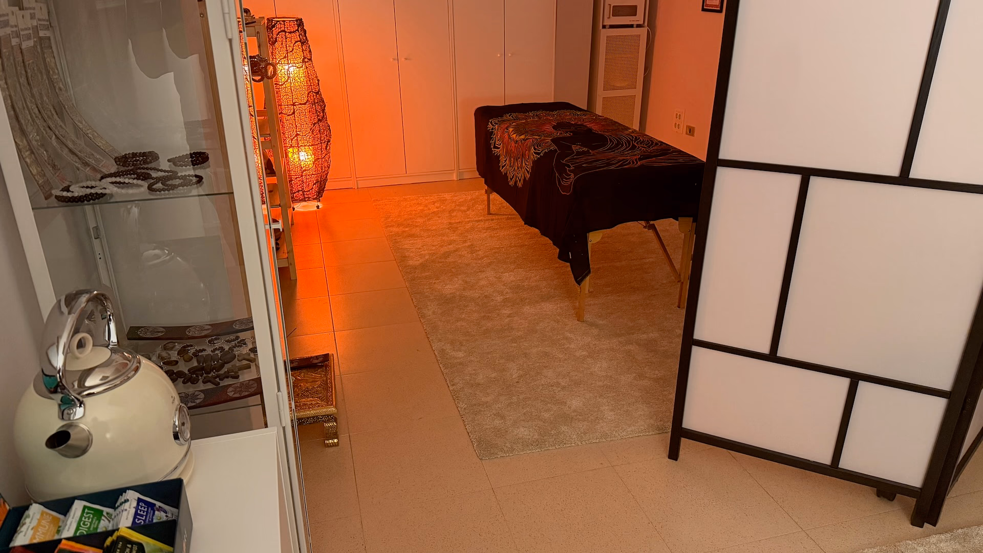 Sala de nuestro centro de Reiki en Bilbao, con la camilla, una lámpara de luz cálida y un biombo de estilo japonés